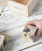 A close up of a block from the Wooden Story Melliferous Plants 
 Puzzle Block set in a child's hand.