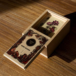 The Wooden Story Melliferous Plants Story Blocks Box with the contents inside placed on a wooden surface. The lid of the wooden box is 3/4 way open, showing the card inside. 