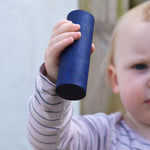 A close up of the large blue cylinder block in a young child's hand. 