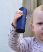 A close up of the large blue cylinder block in a young child's hand. 