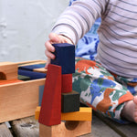 A close up of the child playing with the Wooden Story Rainbow XL Blocks set.