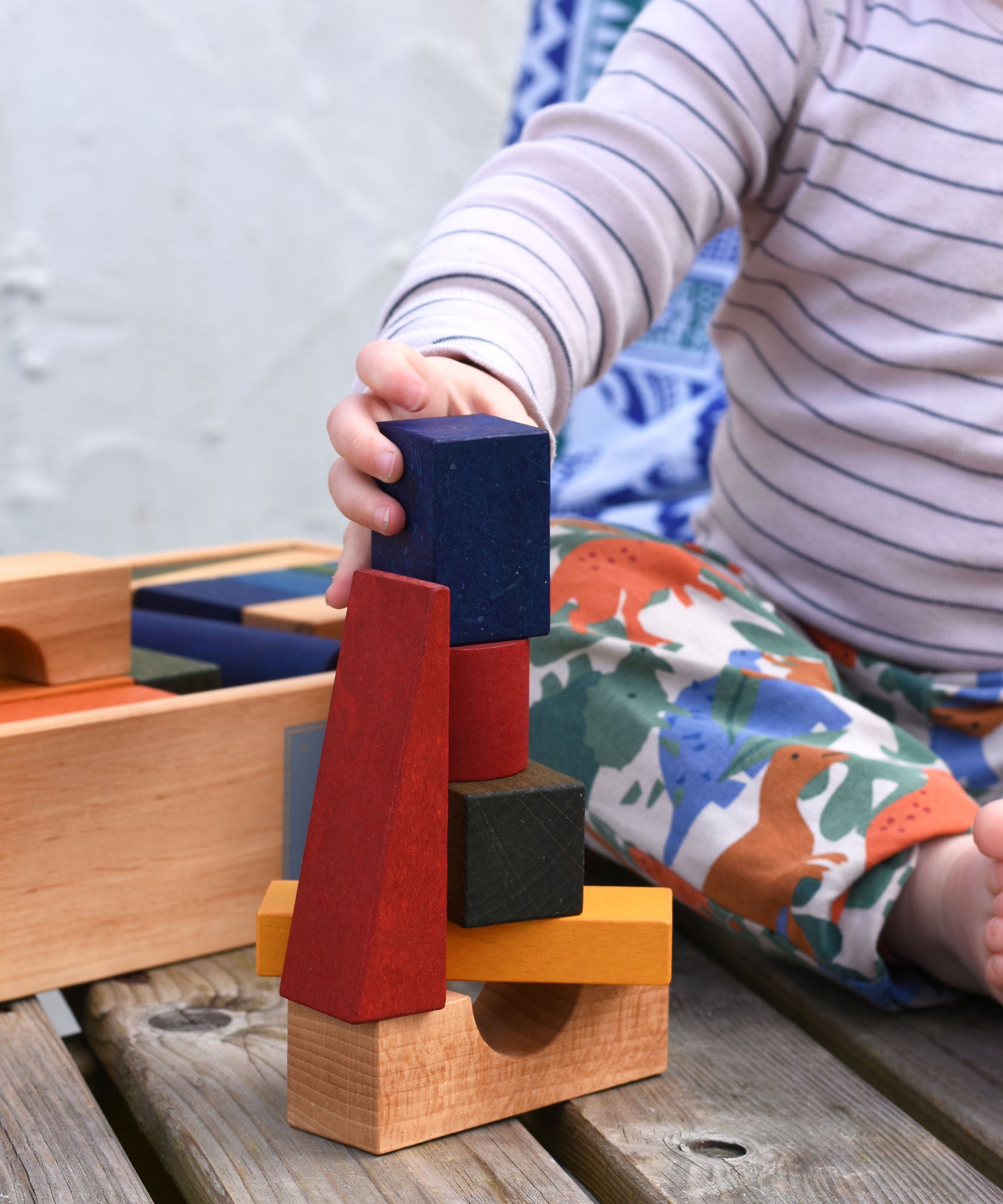 A close up of the child playing with the Wooden Story Rainbow XL Blocks set.