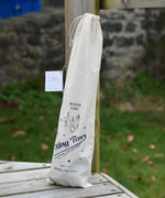 The Wooden Story Ring Toss Game shown in the cotton drawstring storage bag. The bag features beautiful traditional style typography and an illustration of the ring toss game. 