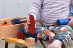 A child playing with the blocks from the Wooden Story Rainbow XL Blocks set. The wooden tray can be seen in the background.