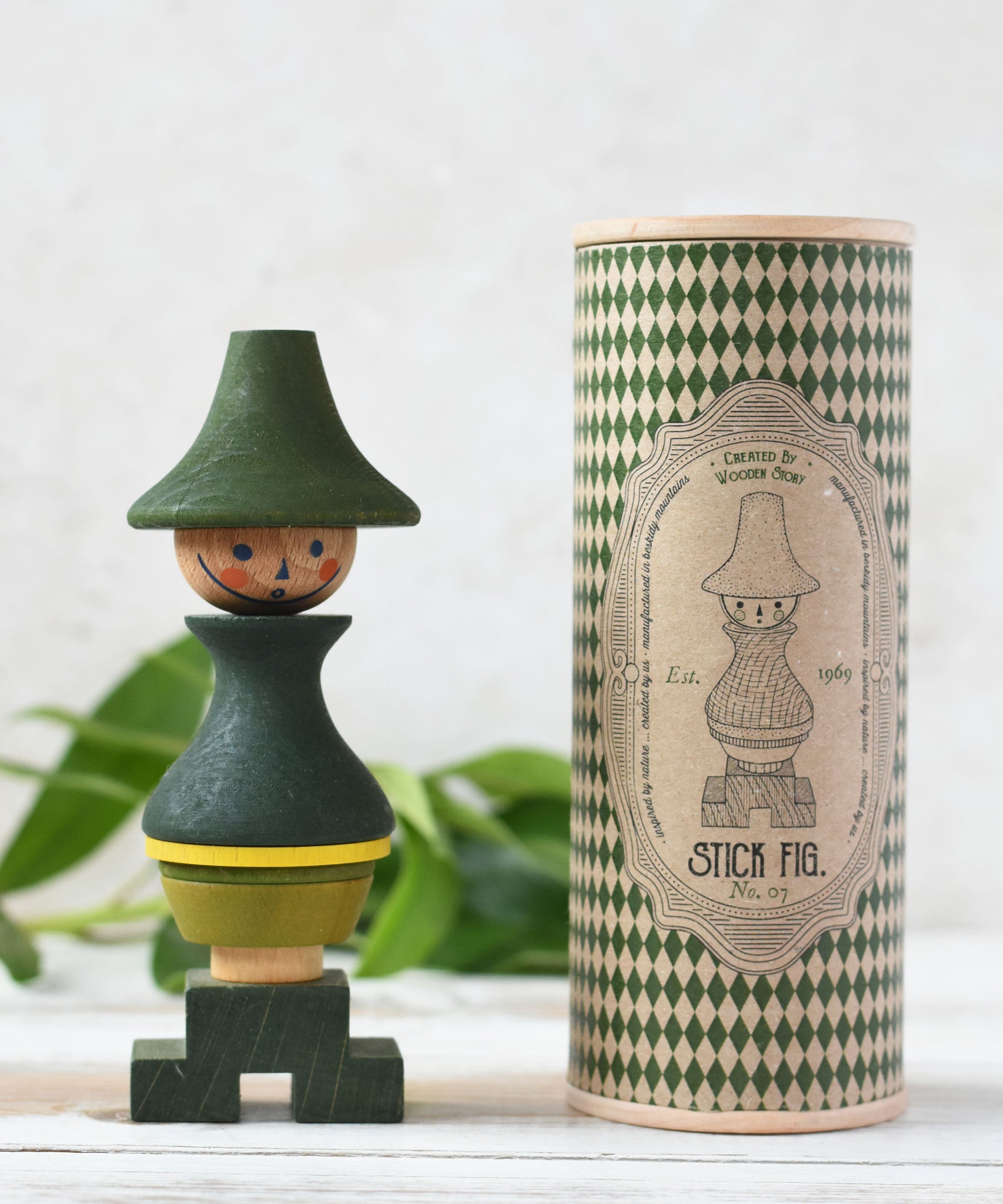 Wooden Story Stacking Toy Stick Figure - No7, a green stacking wooden figure wearing a hat.  The toy is shown next to it's patterned gift box packaging.