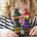 A close up of a child holding the Wooden Story green and purple stick figure stacking toys in their hands. 