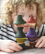 A close up of a child holding the Wooden Story green and purple stick figure stacking toys in their hands. 