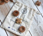 The Wooden Story Tic Tac Toe game shown with the cotton bag base with three pieces on the grid.