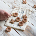 A close up of a child's hand playing with the Wooden Story Tic Tac Toe game.