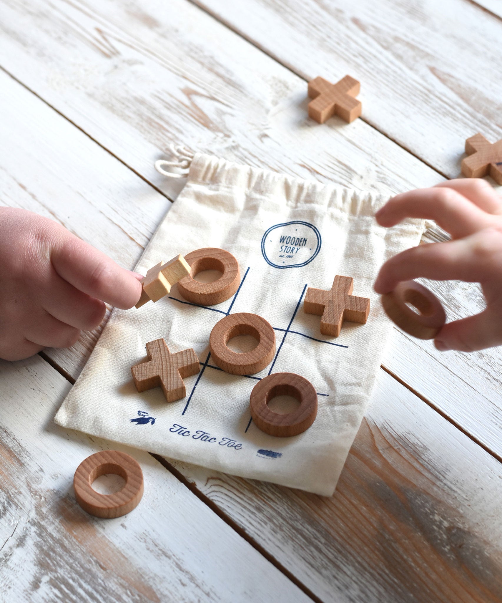 A close up of children playing with the Wooden Story Tic Tac Toe game.