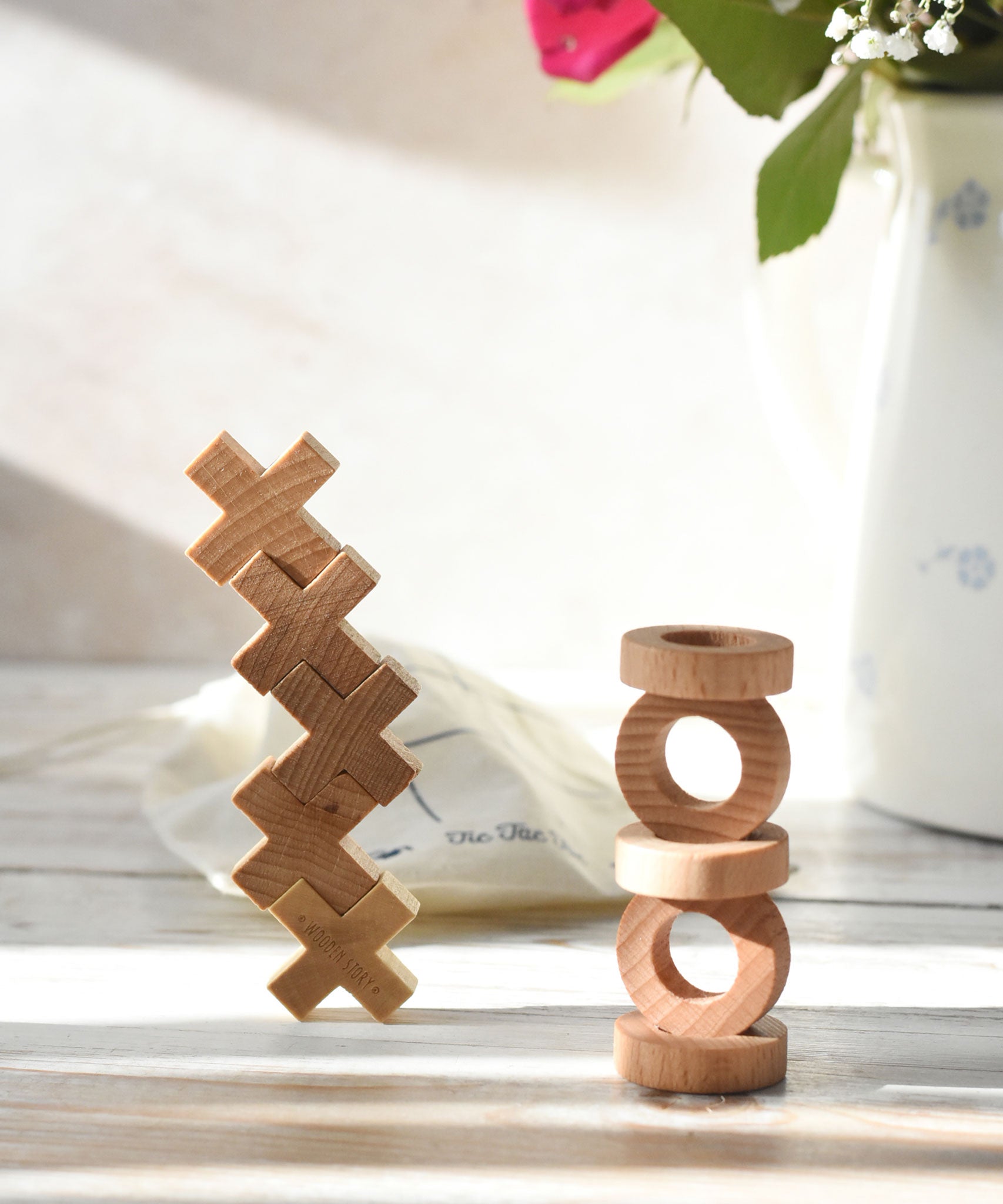 The O and X pieces from the Wooden Story Tic Tac Toe game stacked on top of each other. 