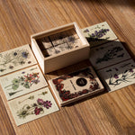 Wooden Story Melliferous Plants Story Blocks Set placed on a wooden surface. The 6 blocks are seen inside the wooden box with the box' lid next to it the 6 cards are placed on the surface outside the box. 