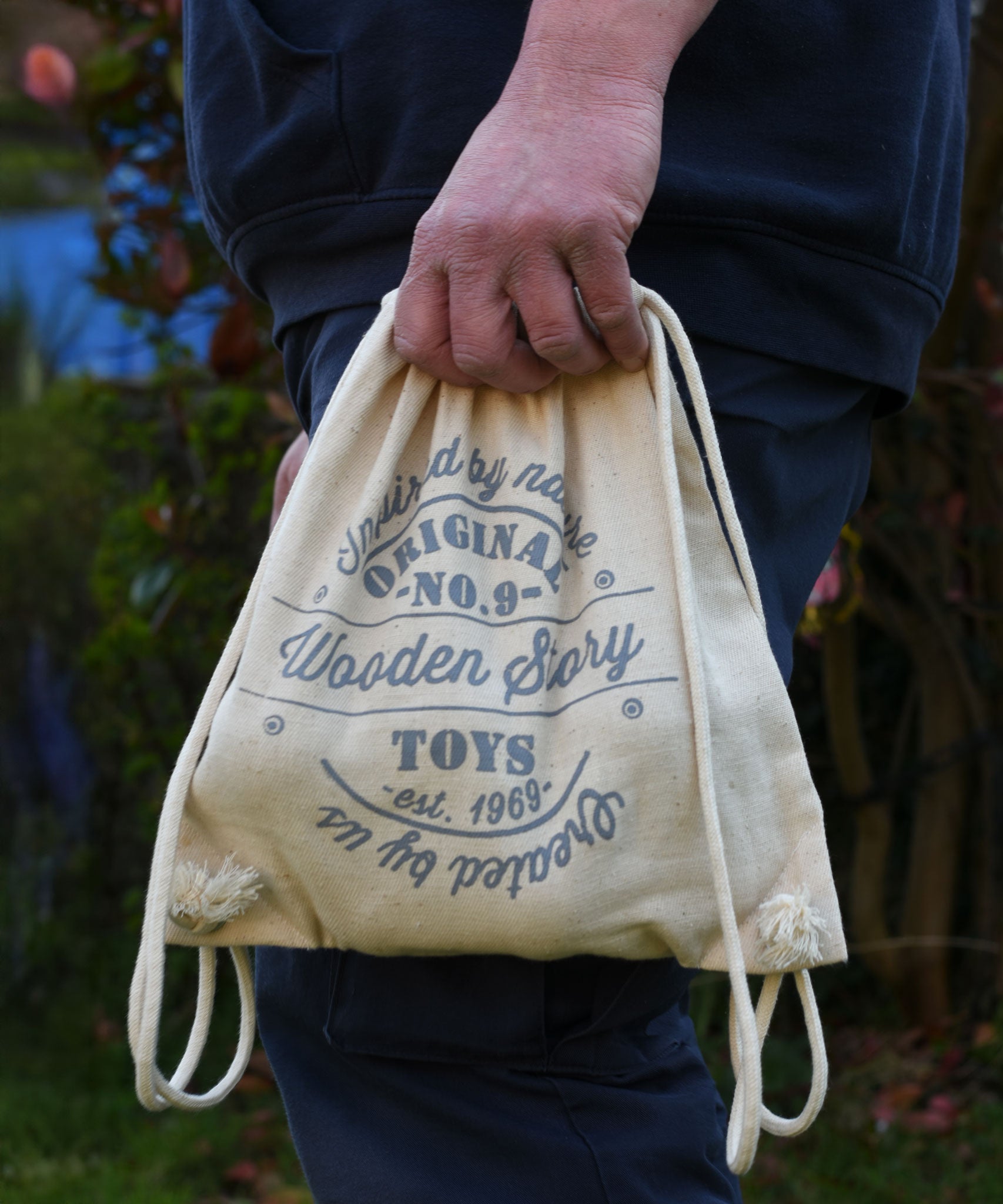 The printed cotton drawstring storage bag being held in an adult's hand. 