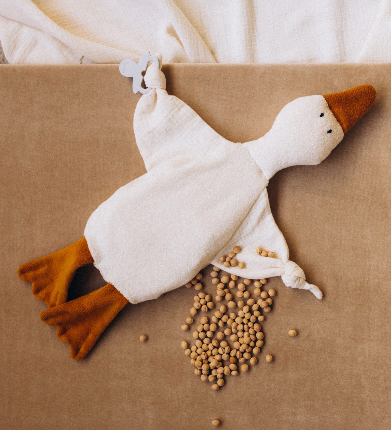 Wooly Organic goose heating pad available at Babipur. A organic cotton heating pad with cherry stones and  playful facial. Features ties on each arm to hold a pacifier. 