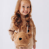 A child wearing the Wooly Organic Kids' Teddy Bear Crossbody Bag. The classic Wooly Organic bear turned into a cute wearable bag for children. A range of Wooly Organic bears and clothing are available at Babipur.