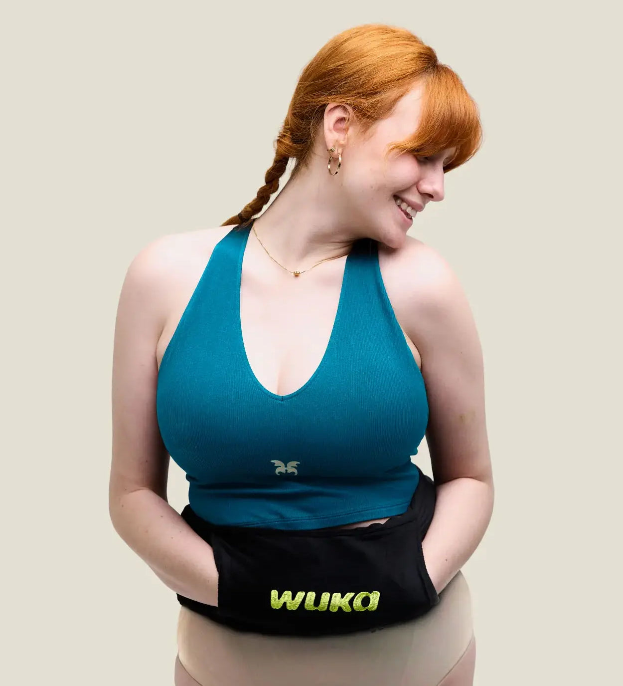 Woman with a Wuka wearable hot water bottle around her waist with hands in the pockets of the fleece sleeve