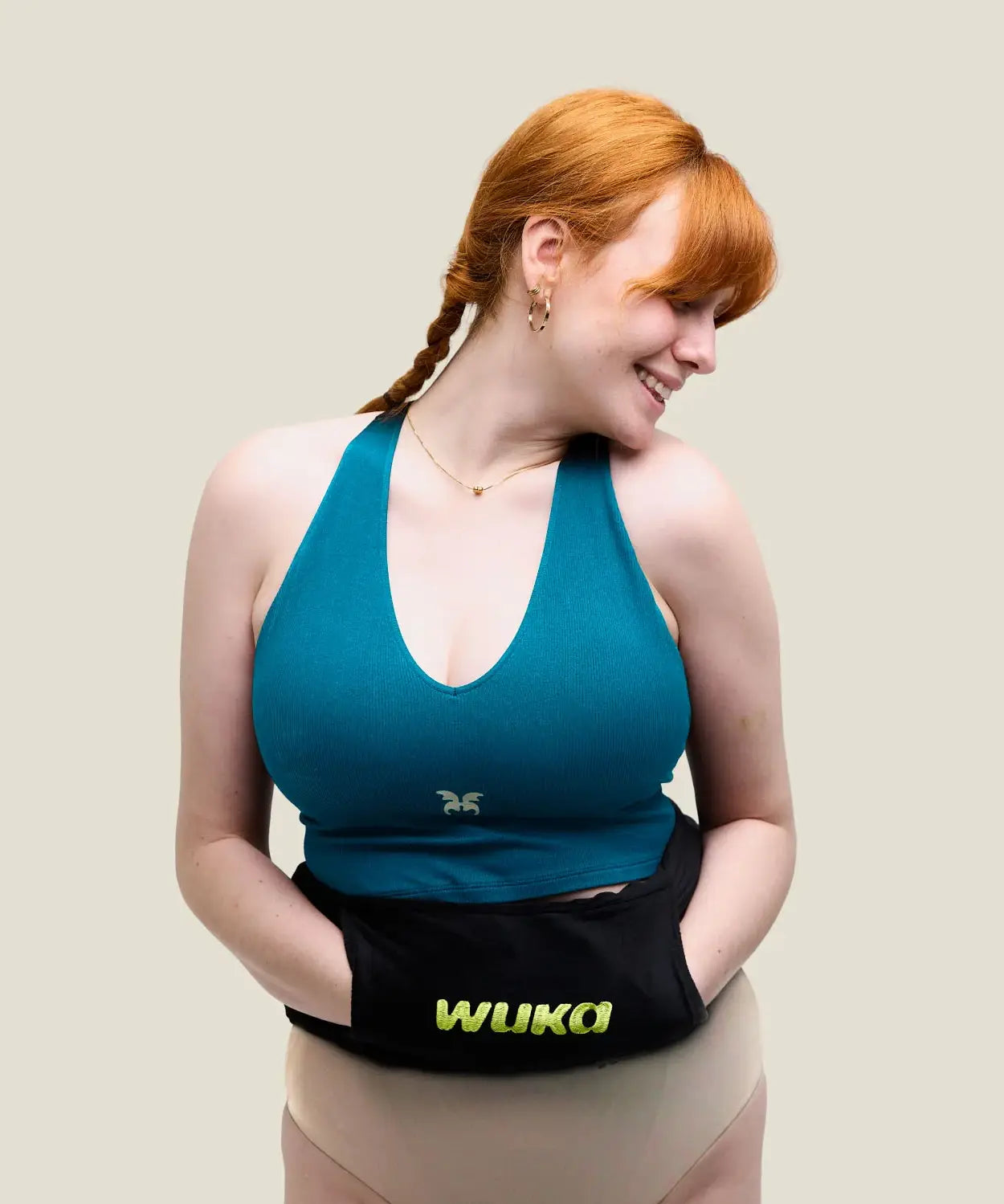 Woman with a Wuka wearable hot water bottle around her waist with hands in the pockets of the fleece sleeve