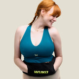Woman with a Wuka wearable hot water bottle around her waist with hands in the pockets of the fleece sleeve