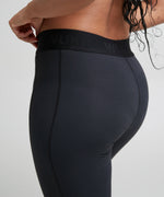 Back of woman wearing the Wuka performance leggings in black showing the elasticated waist band and side pocket