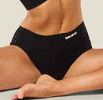 A closeup of a model wearing the WUKA Stretch Midi Brief Period Pants. The model is sat in a yoga position to demonstrate the period knickers' comfort and stretch.