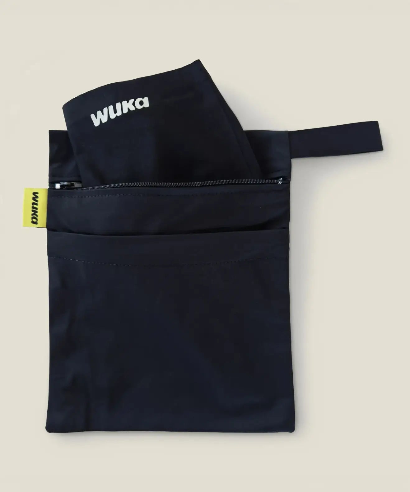 An open Wuka changing bag in black with a period pants in one compartment