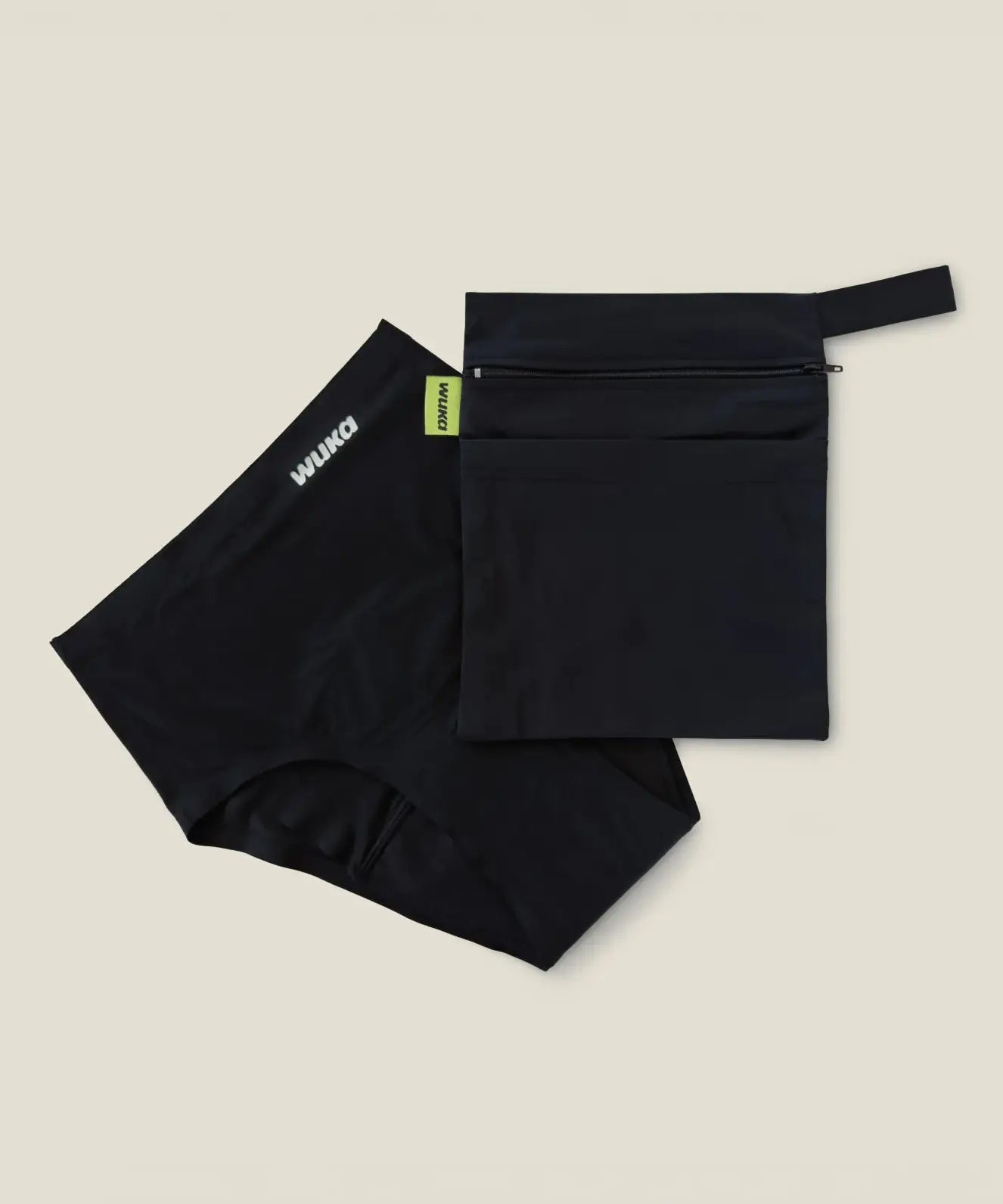 Wuka two pocket changing bag in black laid flat next to a pair of period pants