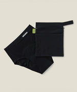 Wuka two pocket changing bag in black laid flat next to a pair of period pants
