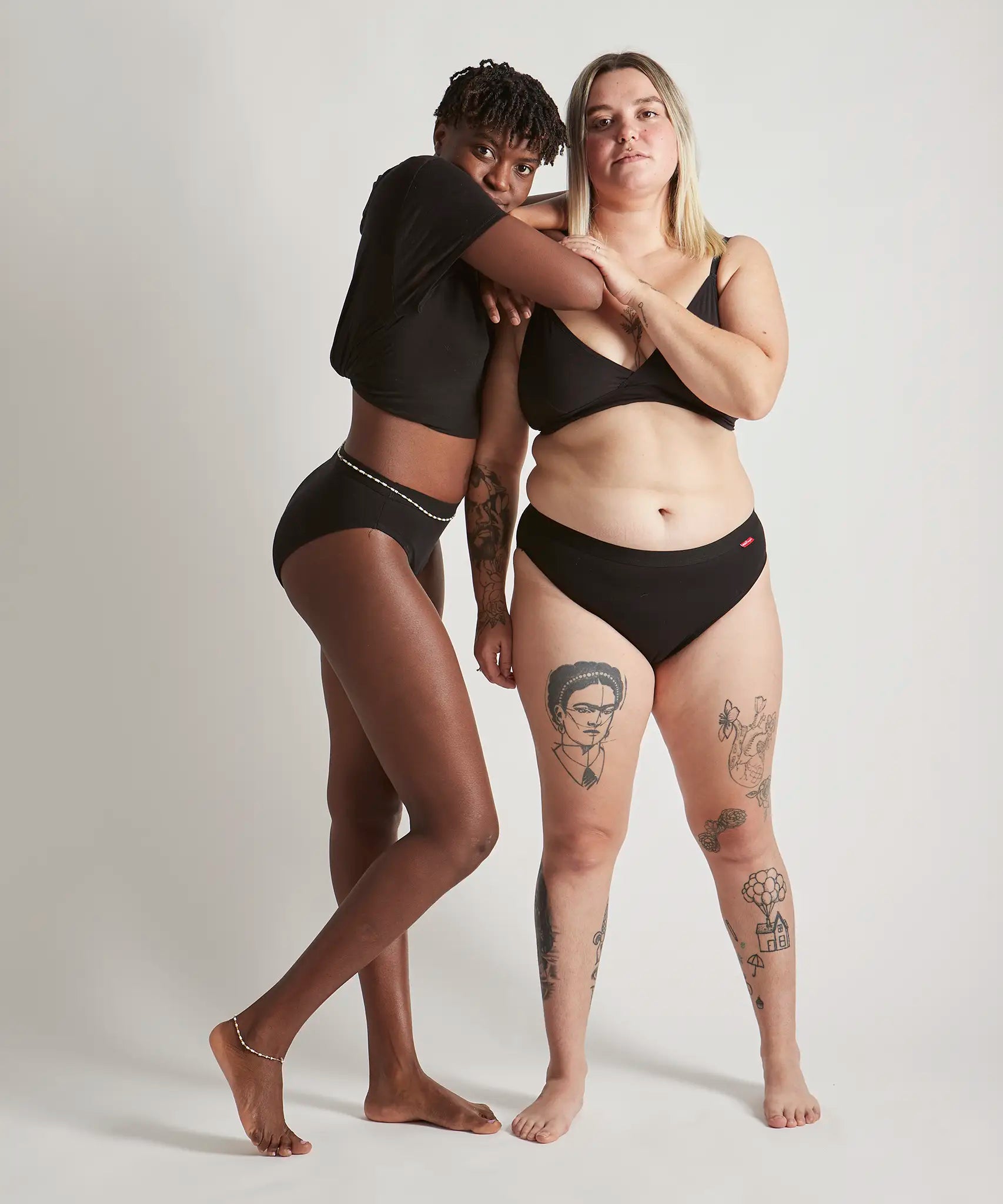 Pair of women wearing the Wuka ultimate bikini style medium flow period brief in black