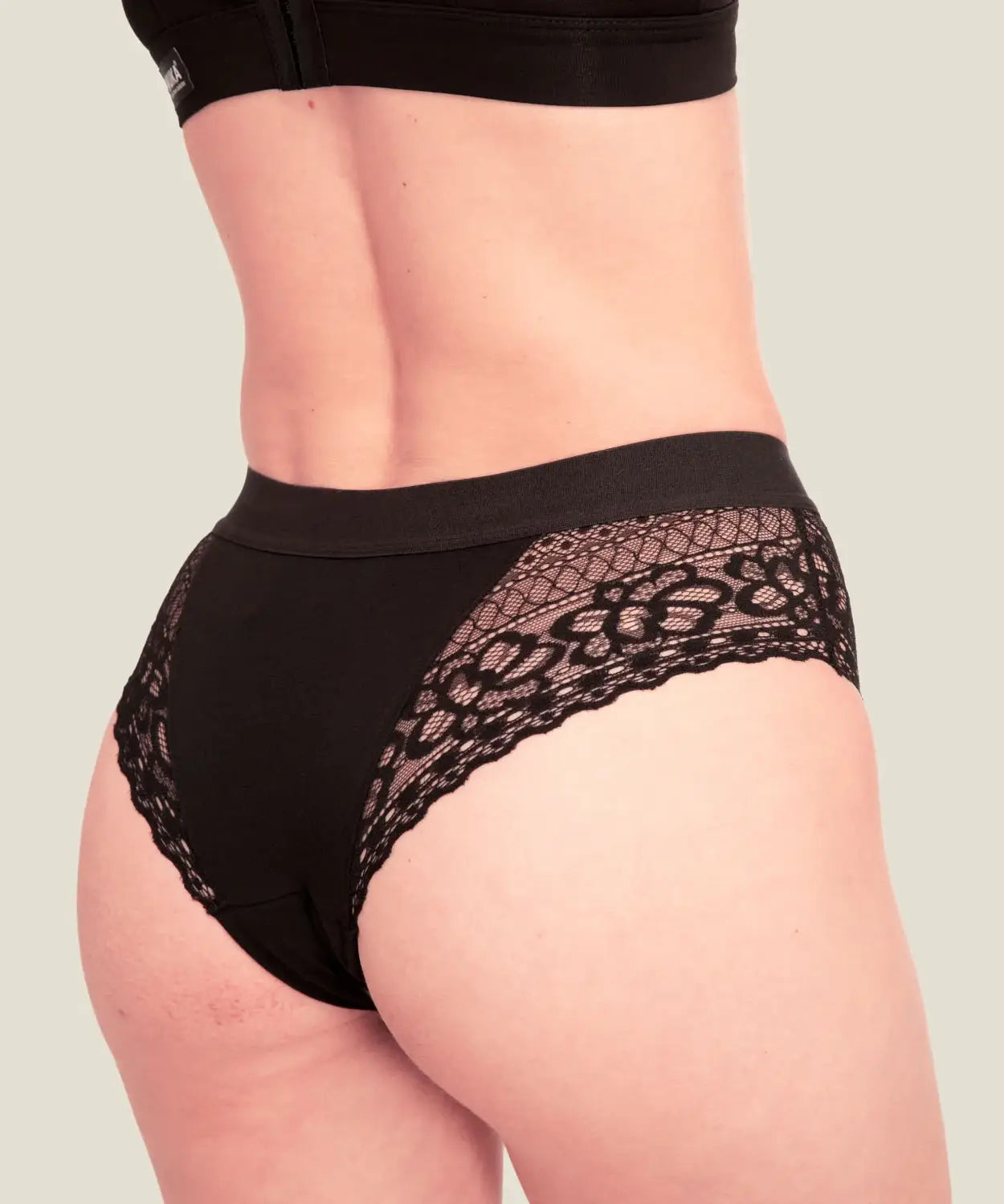 Woman wearing the Wuka ultimate lace midi medium flow period pants showing lace detail on the back