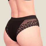 Woman wearing the Wuka ultimate lace midi medium flow period pants showing lace detail on the back