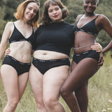 Group of women wearing the WUKA reusable ultimate midi brief period pants in a grassy field