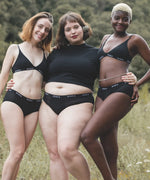 Group of women wearing the WUKA reusable ultimate midi brief period pants in a grassy field
