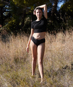 Woman wearing the WUKA reusable ultimate midi brief period pants and standing in a grassy field