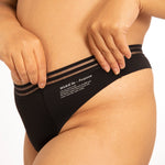 Close up of a woman stood on a white background wearing the WUKA light flow brazilian thong period pants
