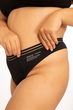 Close up of a woman stood on a white background wearing the WUKA light flow brazilian thong period pants