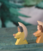 A yellow Ostheimer little angel placed on a green decorative cloth. This wooden figure is part of a large range of expertly hand crafted, Waldorf inspired, wooden toys here at Babipur. 