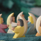 A little yellow angel wooden toy figure from Ostheimer placed on green coloured decorative cloths. Other little angels can be seen in the back. This wooden figure is part of a large range of expertly hand crafted, Waldorf inspired, wooden toys here at Babipur. 