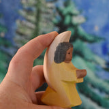 A yellow coloured Ostheimer little angel held in an adult's hand to show scale. This wooden figure is part of a large range of expertly hand crafted, Waldorf inspired, wooden toys here at Babipur. 