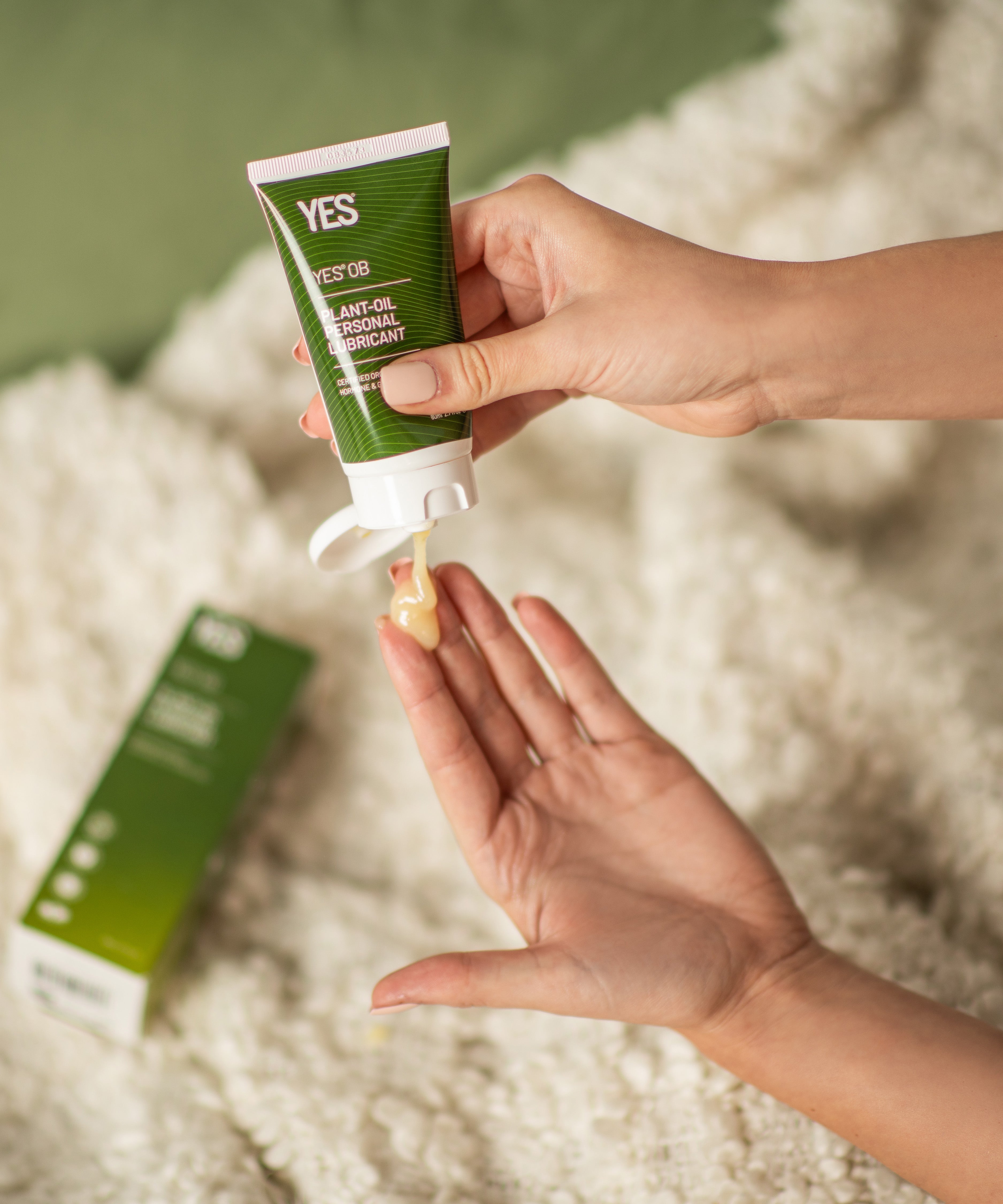 A hand squeezing the Yes oil based organic lubricant out of the tube.