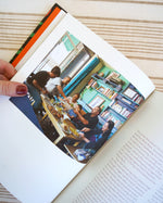A page from the Zaitoun Palestinian Cookbook by activist and author Yasmin Khan. The images inside show Palestinians sitting around a table and enjoying a traditional middle eastern meal.