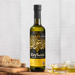 A 250ml bottle of Zaytoun Organic Extra Virgin Olive Oil on a wooden board next to bread and glass dishes containing some olive oil. 
