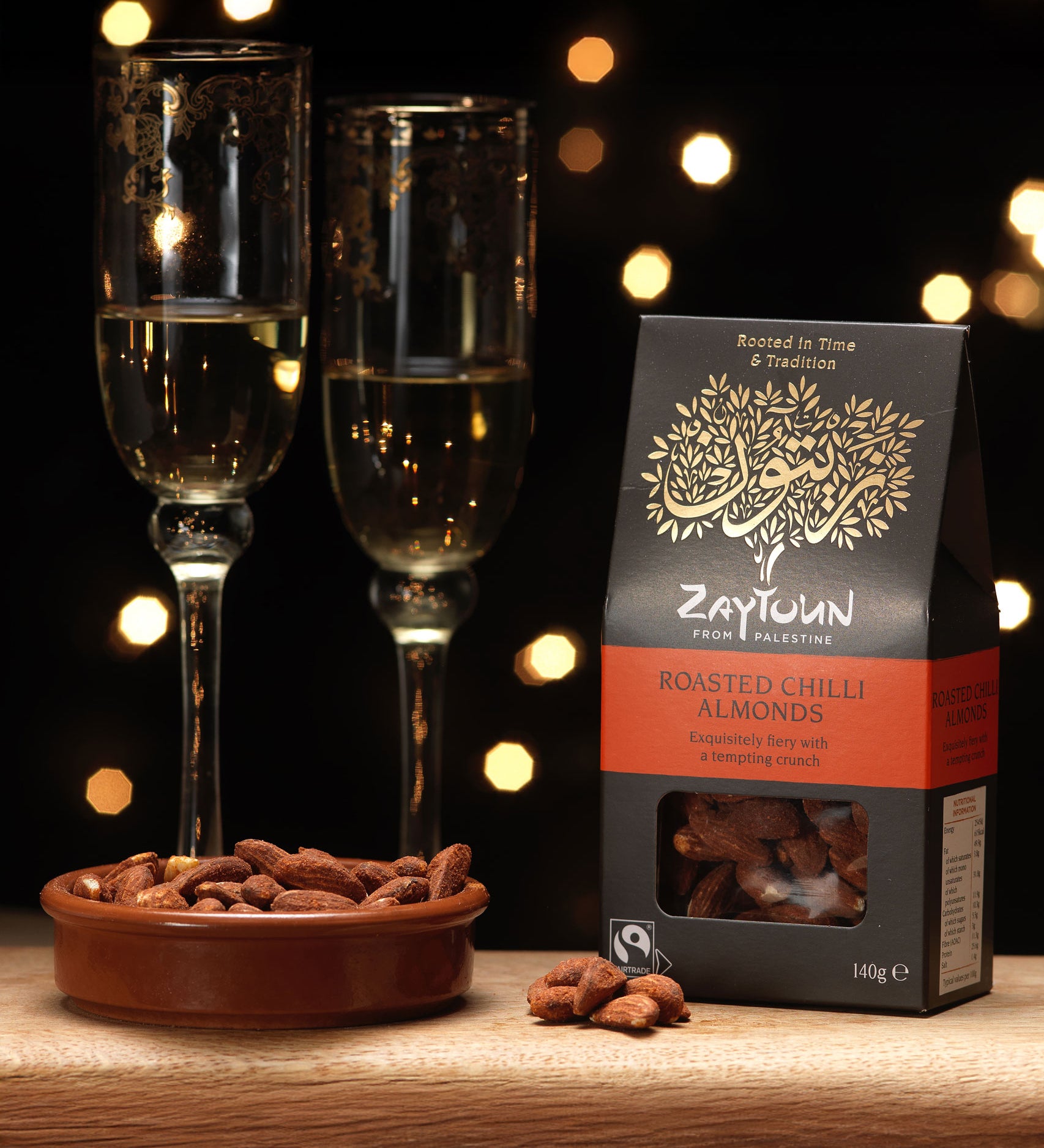 Zaytoun Fairtrade Palestinian roasted chilli Almonds packet pictured next to a bowl filled with the flavoured almonds. We are proud stockists of Zaytoun olive oil and produce here at Babipur. 