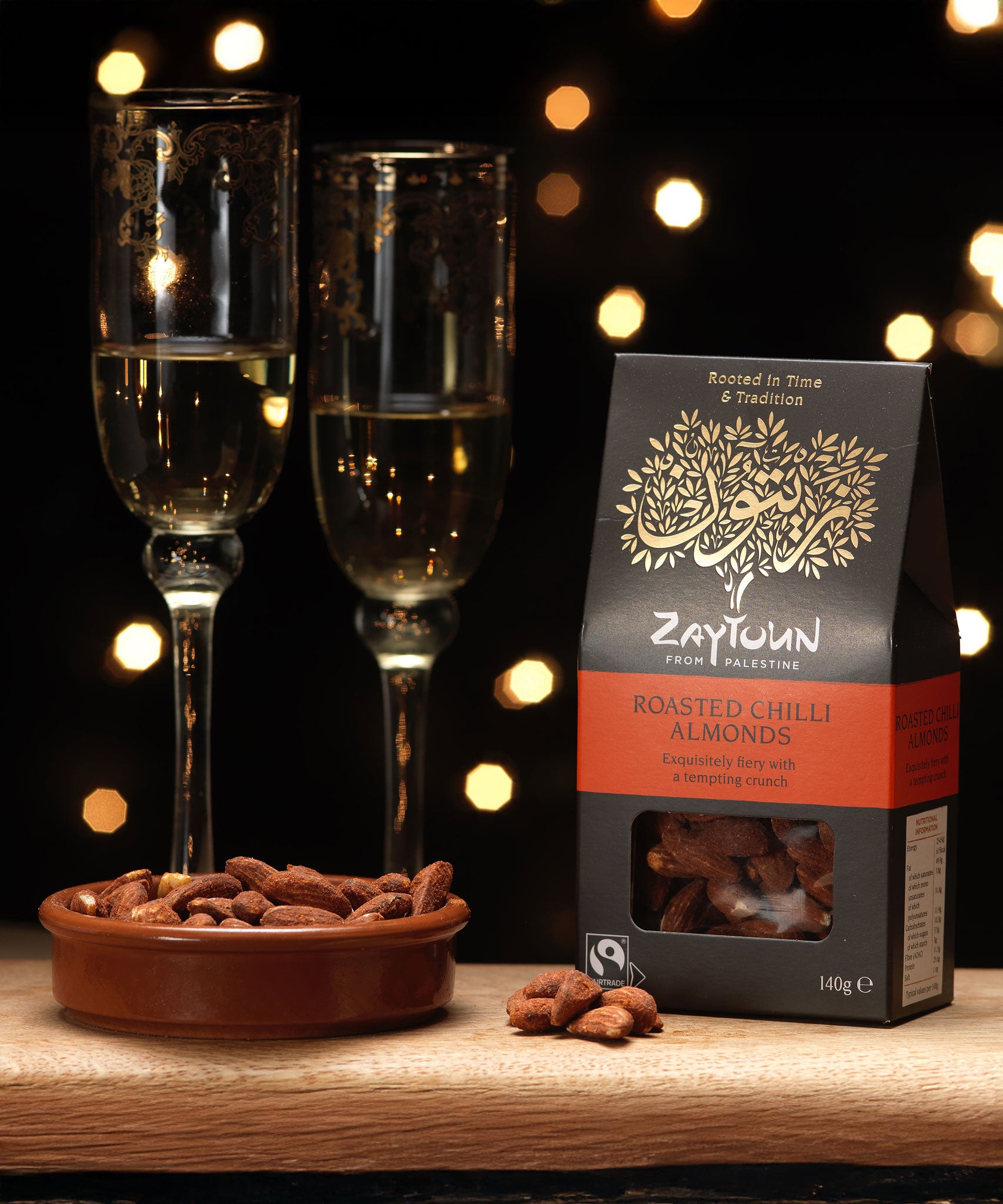 Zaytoun Fairtrade Palestinian roasted chilli Almonds packet pictured next to a bowl filled with the flavoured almonds. We are proud stockists of Zaytoun olive oil and produce here at Babipur. 