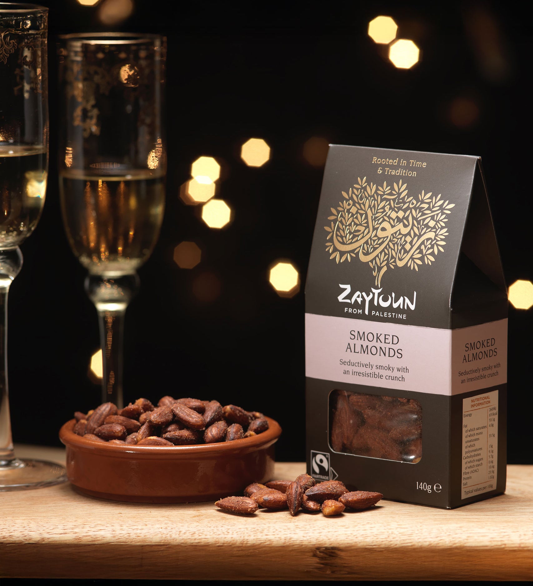 A packet of Zaytoun Fairtrade Palestinian Smoked Almonds next to bowl filled with them. We are proud stockists of Zaytoun olive oil and produce here at Babipur. 