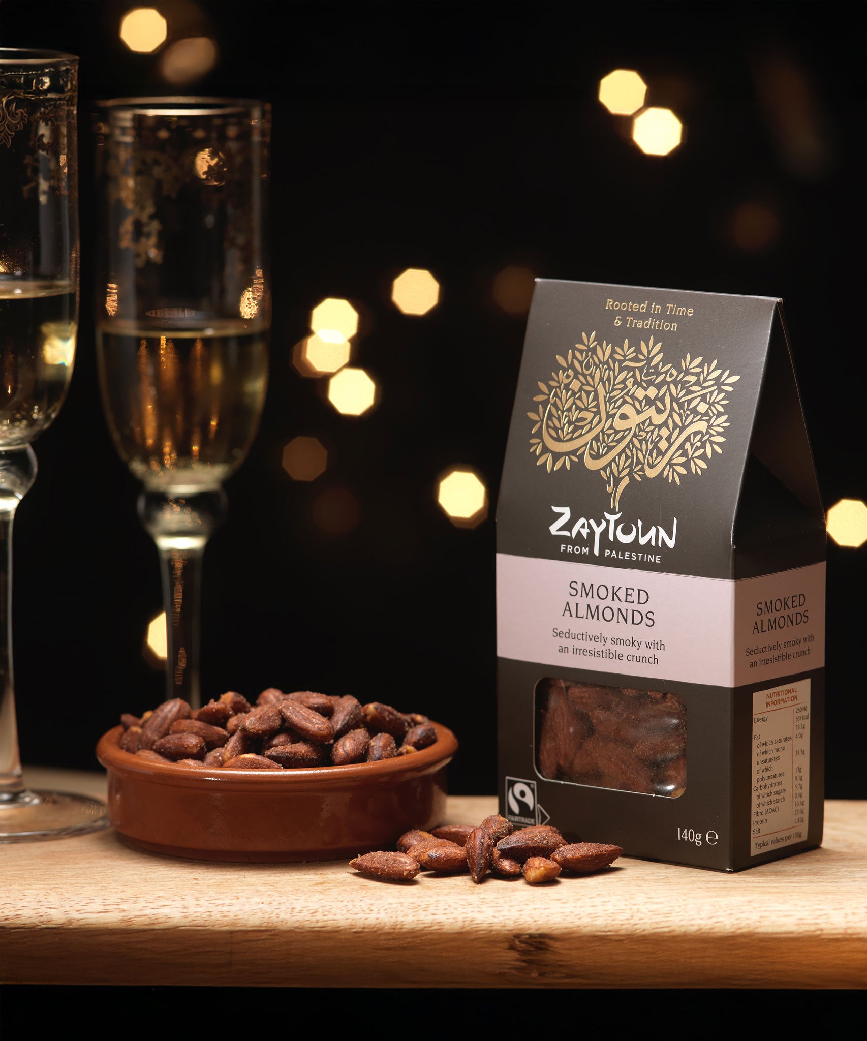 A packet of Zaytoun Fairtrade Palestinian Smoked Almonds next to bowl filled with them. We are proud stockists of Zaytoun olive oil and produce here at Babipur. 